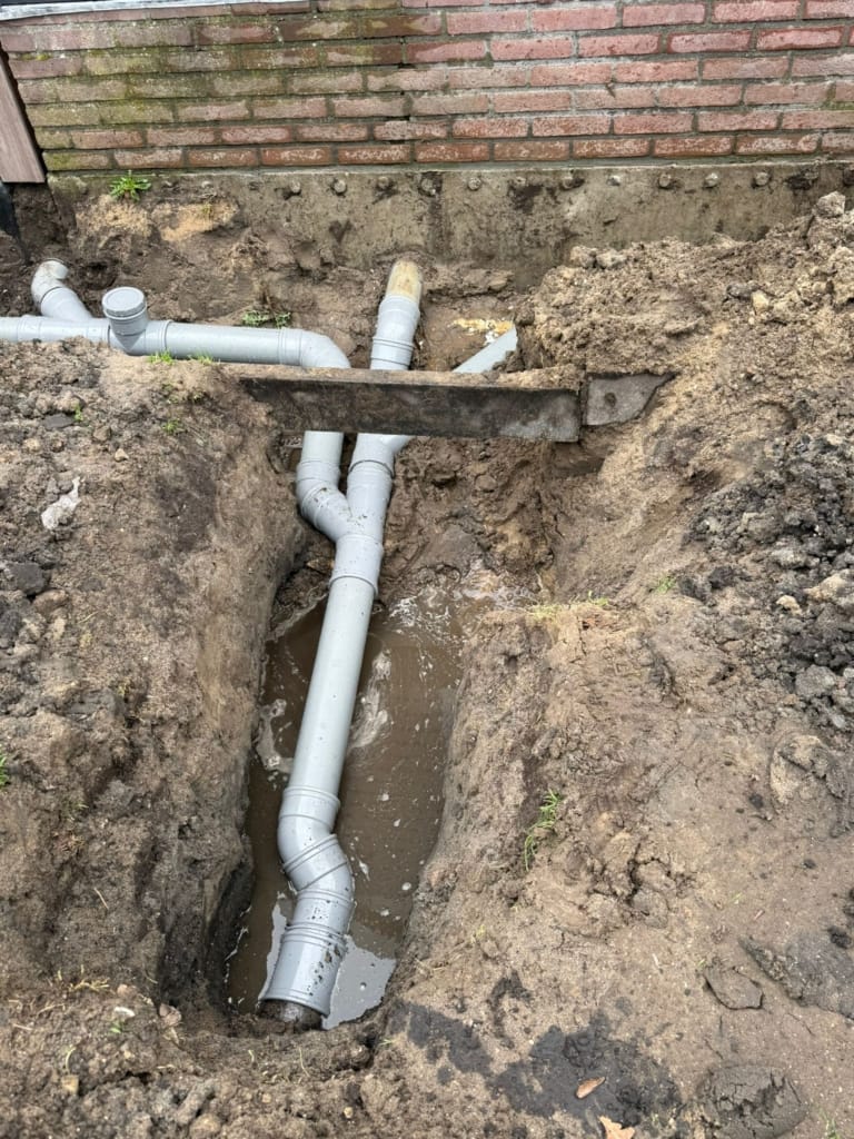 Grijs PVC afvoerpijpen in uitgegraven sleuf